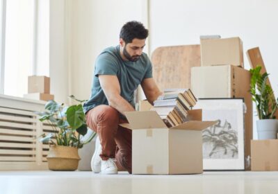 A man packs books into an open cardboard box