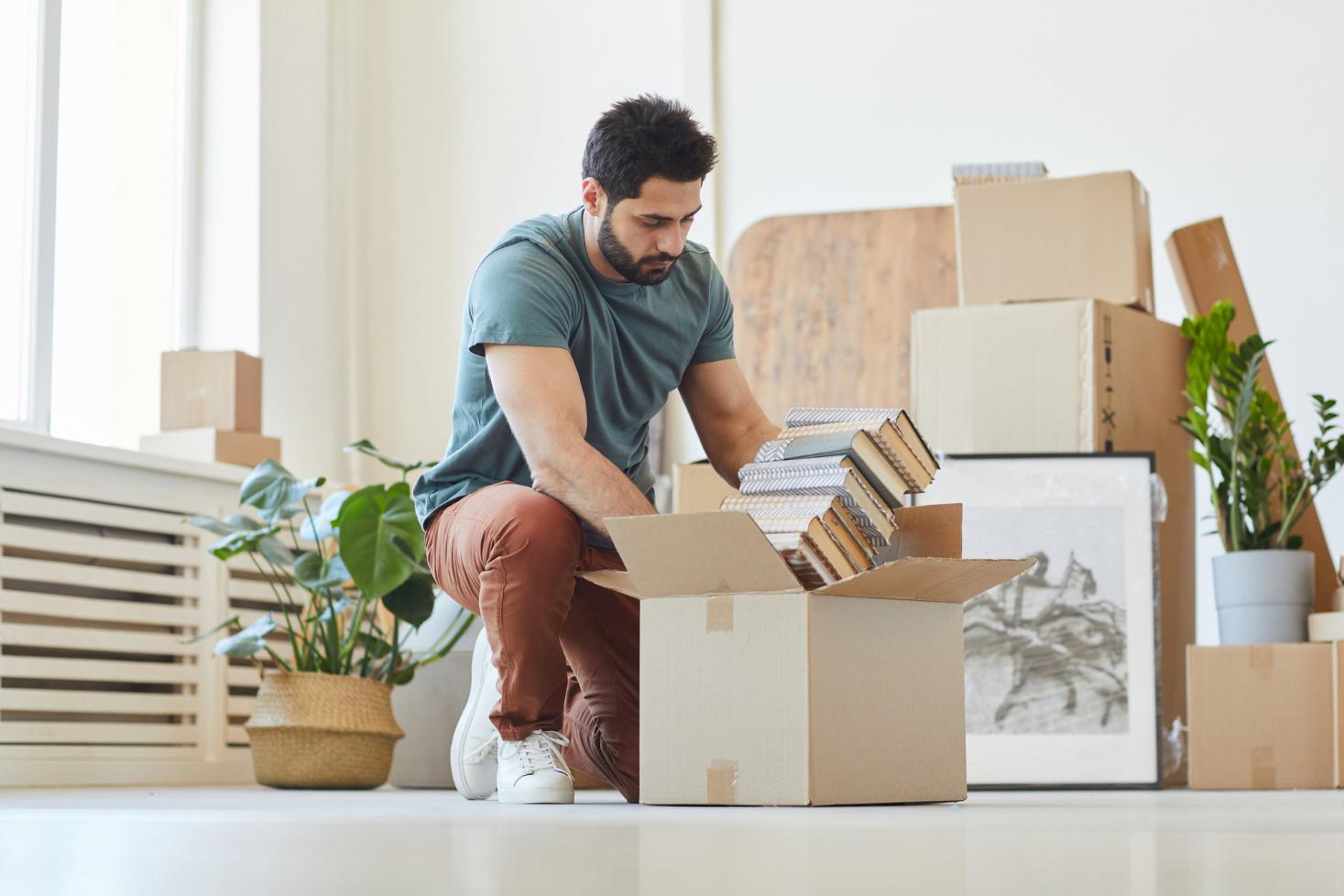 A man packs books into an open cardboard box