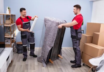 Two professional movers packing up a living room.