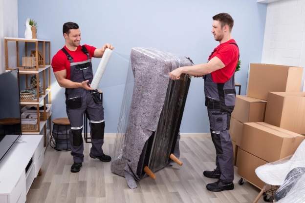 Two professional movers packing up a living room.